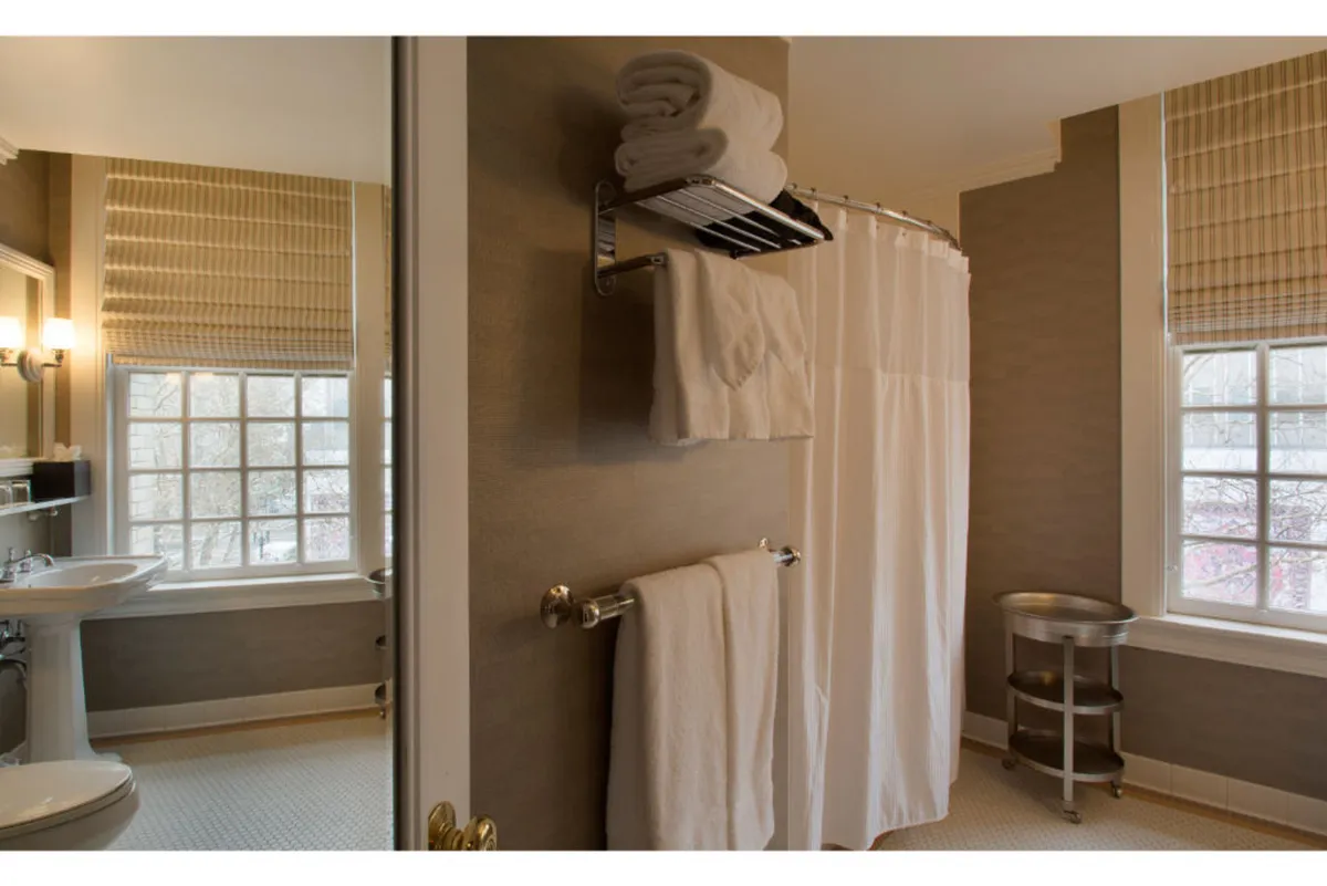 This image features a bathroom with a clear view of the shower area, a sleek sink, and a window letting in natural light. The overall mood is calm and refreshing, with the shower and sink area suggesting opportunities for both a revitalizing shower and morning or evening routines. Elements of the image speak to self-care and relaxation.